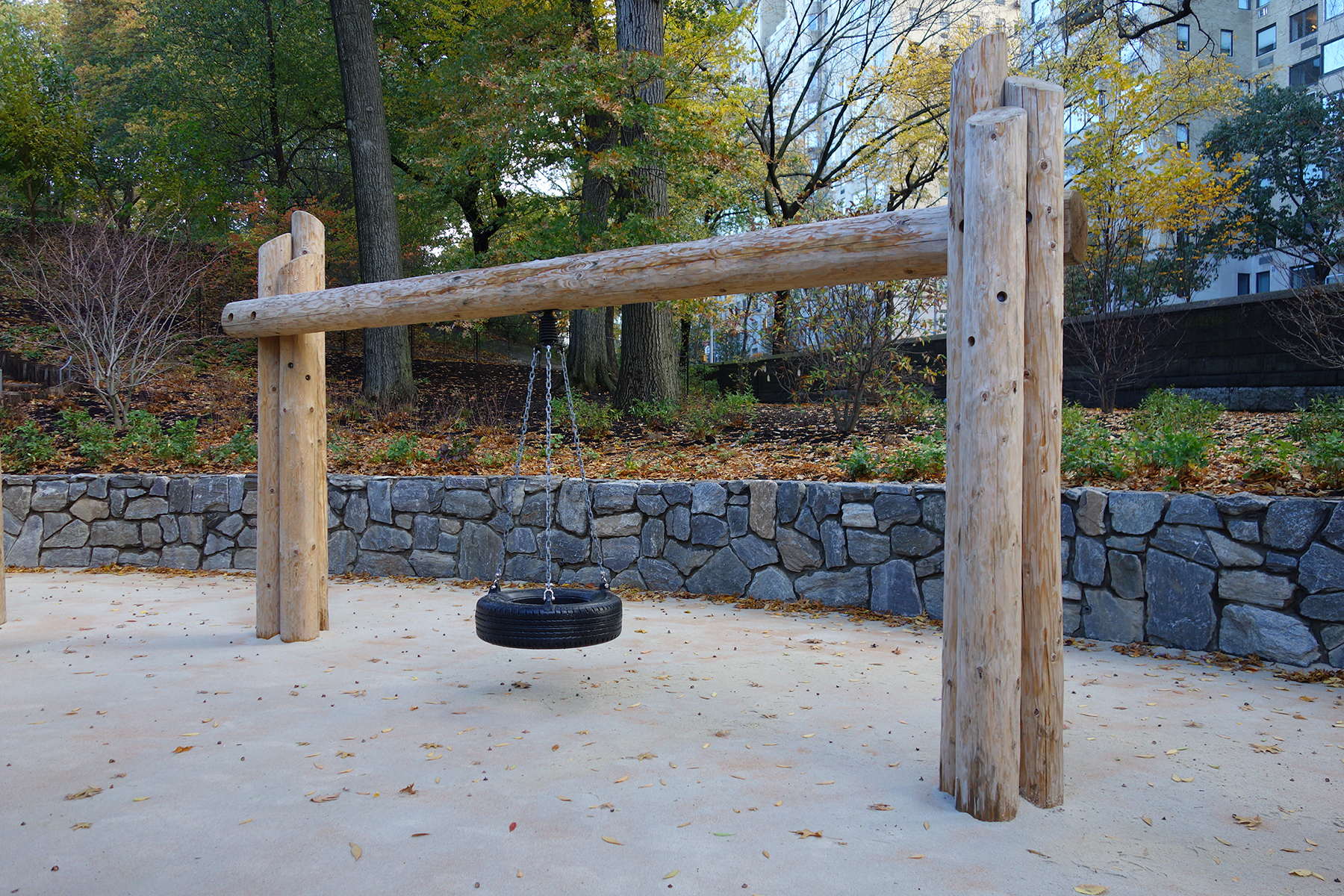 Stone wall in park by swing