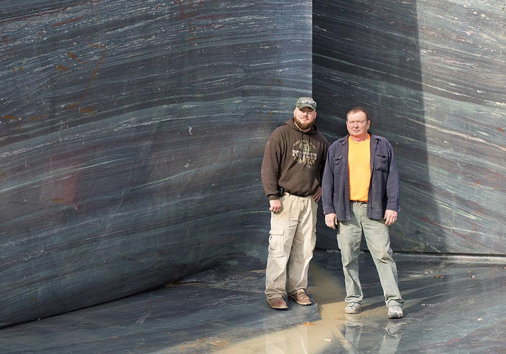 two quarry workers in front of granite slab