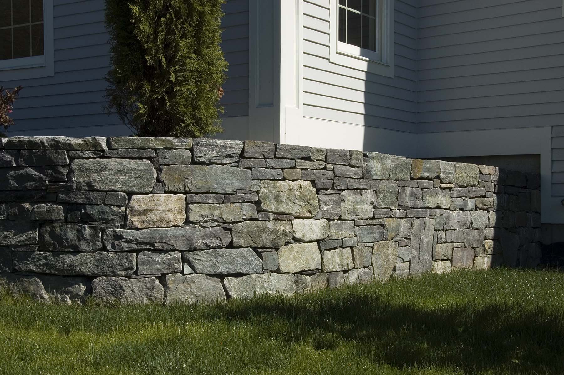 saratoga granite mosaic natural stone retaining wall outside residential home