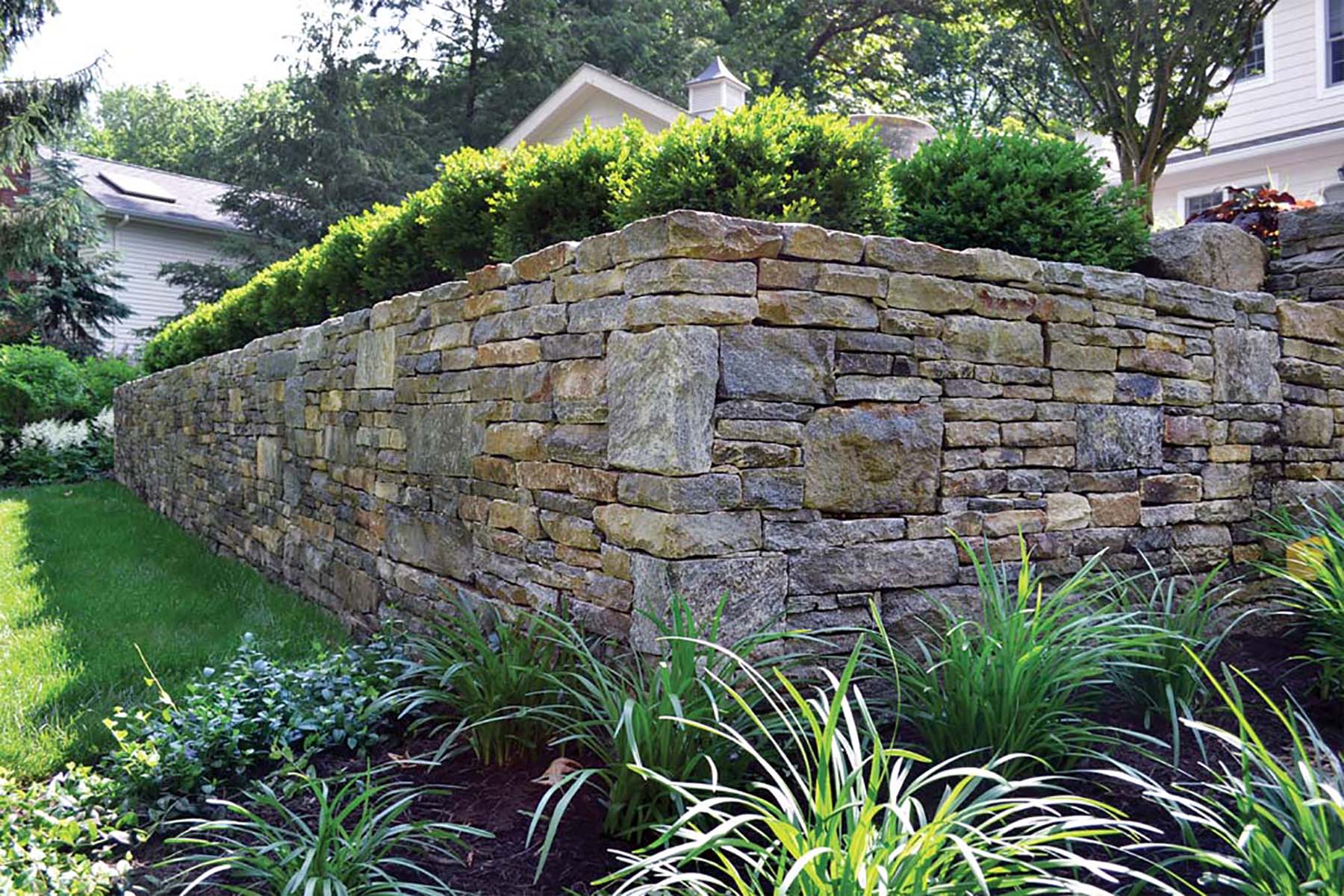 natural stone Ticonderoga granite retaining wall in residential backyard